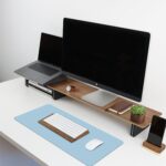 Black leather desk pad protecting a wooden desk, with a laptop and mouse on its surface, viewed from above.