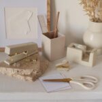 A complete 10-piece KIBAGA desk organizer set in beige and gold, including a stapler, scissors, pen holder, and tape dispense