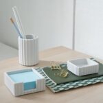 A set of three gray concrete desk organizers, including a pen holder, a notes holder, and a small dish for clips, arranged on