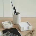 A set of three gray concrete desk organizers, including a pen holder, a notes holder, and a small dish for clips, arranged on