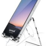 A clear acrylic cell phone stand holding a smartphone on a desk, showcasing its transparent design and cable management.