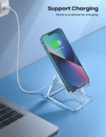 A clear acrylic cell phone stand holding a smartphone on a desk, showcasing its transparent design and cable management.